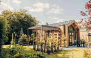 Modernes Tiny House mit Terrasse und Whirlpool im Veluwepark de Bosgraaf, Niederlande, umgeben von Natur.