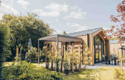 Tiny house moderne Tiny Lodge avec terrasse à Veluwepark de Bosgraaf, Pays-Bas, entourée de verdure.