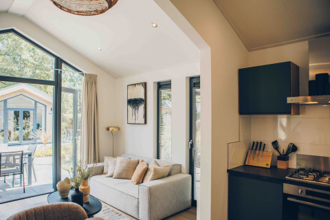 Bright, modern living area and kitchen in a Tiny Lodge at Veluwepark de Bosgraaf, overlooking the garden.