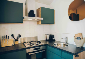 Cocina pequeña y moderna con estufa, horno y gabinetes verdes en Tiny Lodge, Veluwepark de Bosgraaf, Países Bajos.
