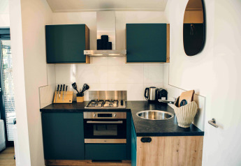 Cucina compatta e moderna con mobili verdi e lavandino tondo nella Tiny Lodge a Veluwepark de Bosgraaf.