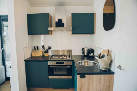 Kompakte, moderne Küche mit grünen Schränken und Gasherd in einer Tiny Lodge im Veluwepark de Bosgraaf.