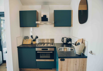Cocina moderna y compacta con armarios verdes y fregadero redondo en Tiny Lodge, Veluwepark de Bosgraaf.