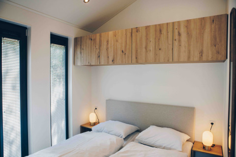 Dormitorio en Tiny Lodge con jacuzzi en Veluwepark de Bosgraaf, Países Bajos, con dos camas y armarios.