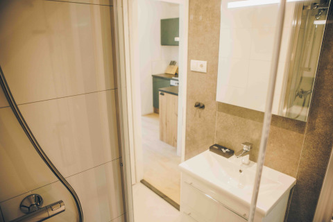Blick vom Badezimmer in die Küche eines Tiny Lodge mit Whirlpool im Veluwepark de Bosgraaf, Niederlande.