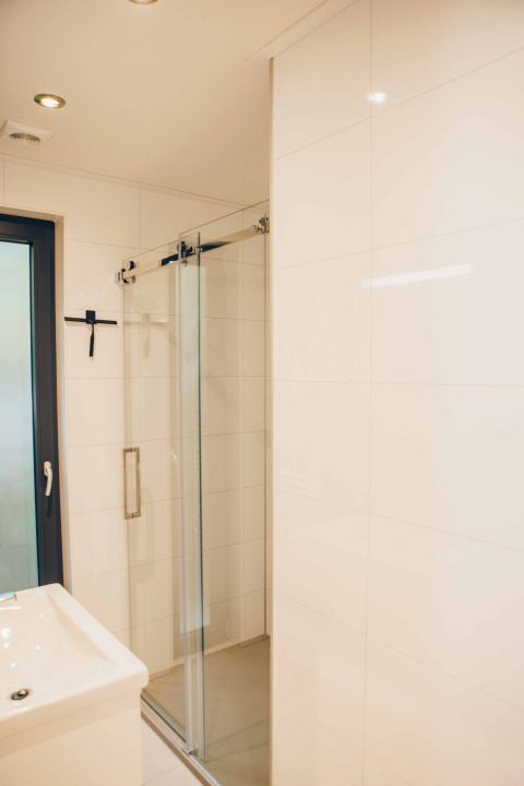 Modernes Badezimmer mit Dusche und Glastür im Tiny Lodge mit Whirlpool im Veluwepark de Bosgraaf, Niederlande.