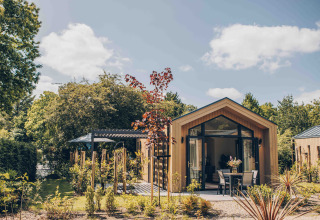 Tiny Lodge avec jacuzzi au Veluwepark de Bosgraaf, Pays-Bas, entouré d’arbres et d’un jardin paisible.