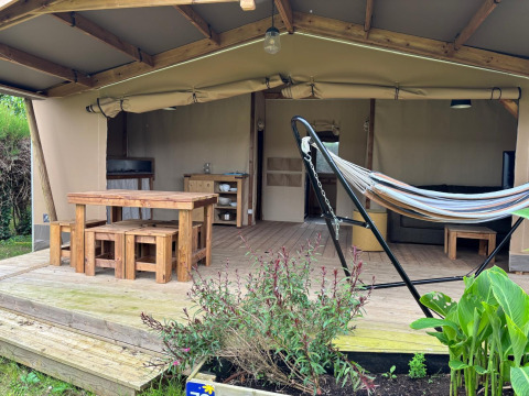 Safari tent Ecolodge cabine Cotton CONFORT at Flower Camping Les Ilates with wooden furniture and hammock.