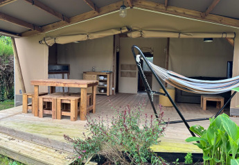 Tente safari Ecolodge cabine Cotton CONFORT au Flower Camping Les Ilates avec mobilier en bois et hamac.