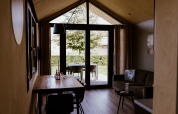 Interior of a lodge with dining table, sofa, and garden view at Holiday park Eigen Wijze, Netherlands.