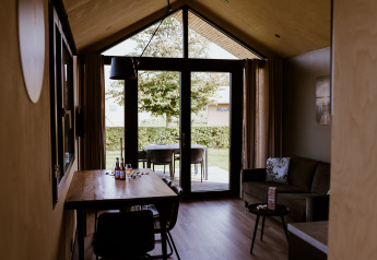 Interior of a lodge with dining table, sofa, and garden view at Holiday park Eigen Wijze, Netherlands.