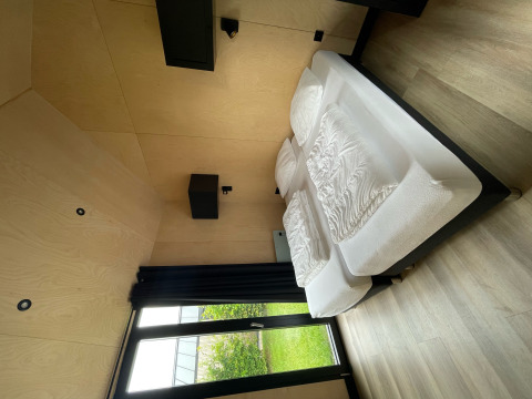 Moderne slaapkamer in Tiny House XL met grote ramen en uitzicht op tuin bij Holiday park Eigen Wijze, Nederland.