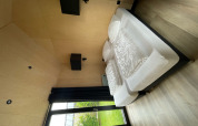 Modern bedroom in Tiny House XL with large windows and garden view at Holiday park Eigen Wijze, Netherlands.