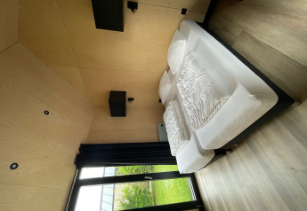 Modernes Schlafzimmer im Tiny House XL mit Blick auf den Garten im Holiday Park Eigen Wijze, Niederlande.