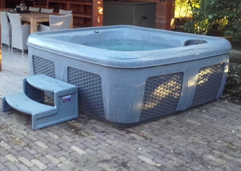 Udendørs jacuzzi med trappe på terrasse ved siden af spisebord på Tiny house XL i ferieparken Eigen Wijze.