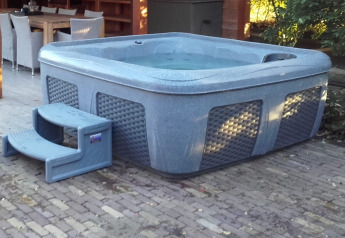 Jacuzzi im Freien mit Stufen auf Terrasse neben Esstisch im Tiny house XL im Ferienpark Eigen Wijze, Niederlande.