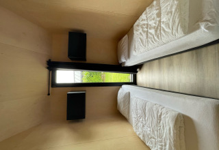 Camera moderna a due letti singoli con finestra sul giardino in Tiny house XL al Holiday park Eigen Wijze.