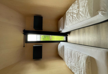 Modernes Schlafzimmer mit zwei Einzelbetten und Gartenblick in der Tiny house XL Lodge in den Niederlanden.