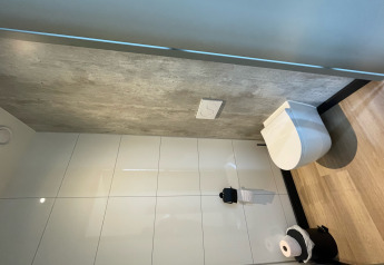 Modern restroom with wall-mounted toilet, tiled walls, and wood floor at Tiny house XL, Holiday park Eigen Wijze.