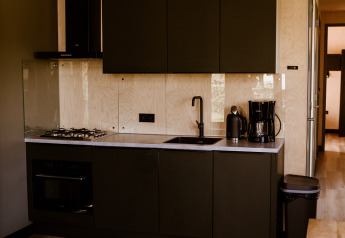 Modern black kitchen in Tiny House XL with wood accents at Holiday park Eigen Wijze, Netherlands.