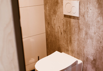 Modern bathroom with wall-mounted toilet and flush panel inside Tiny House XL at Holiday park Eigen Wijze, Netherlands.