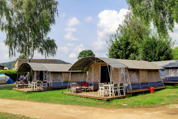 Foto von modernen Zelten mit Holzterrasse und Gartenmöbeln auf einem lodgeähnlichen Campingplatz.