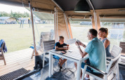Une famille joue aux cartes à une table dans une tente lodge confortable lors de vacances en camping.