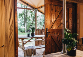 Gezellige houten veranda met tuinzicht, gezien door een open deur bij Beerze Bulten vakantiepark in Overijssel.