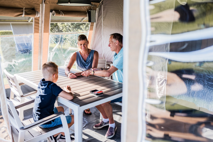Eine Familie sitzt in einer Lodge am Tisch, spielt Karten und verbringt gemeinsam Zeit im Urlaub.