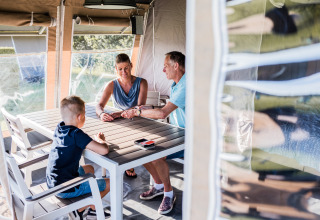 Una famiglia è seduta attorno a un tavolo in un lodge, gioca a carte e trascorre del tempo insieme.