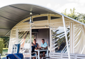 To personer nyder et måltid sammen i en komfortabel lodge med moderne møbler og udendørs terrasse.