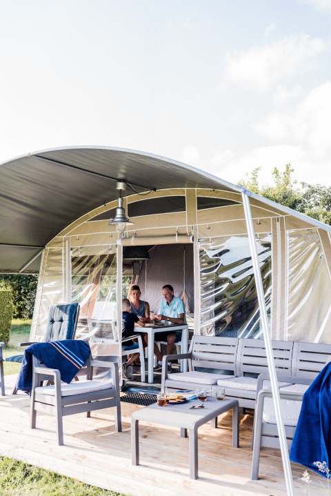 Due persone si godono un pasto insieme in un lodge moderno con arredi da esterno su una terrazza in legno.