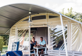Due persone si godono un pasto insieme in un lodge moderno con arredi da esterno su una terrazza in legno.