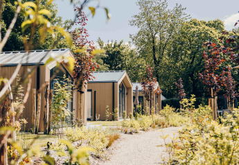 Tiny Lodge mit Whirlpool im Veluwepark de Bosgraaf in den Niederlanden, umgeben von Sommergrün.