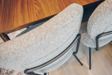 Two soft, light gray upholstered chairs with black metal frames around a wooden table in a cozy lodge.