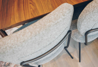 Twee comfortabele, lichtgrijze stoelen bij een houten tafel op een lichte vloer in een gezellige lodge.