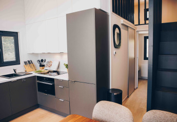 Cucina moderna di lodge con mobili grigi, pensili bianchi e scala nera che porta a un soppalco.