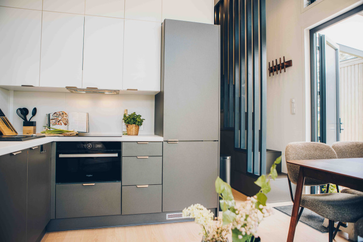 Modern lodge kitchen with stylish cabinets, oven, dining area, and plants beside an open front door.