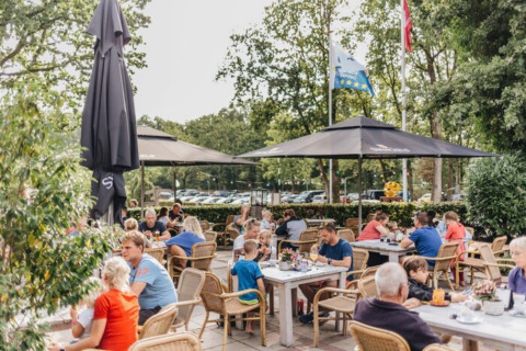 Gezellige vakantiegasten genieten samen op het zonnige terras van Beerze Bulten in Overijssel, Nederland.