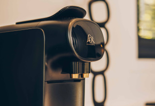 Schwarze Philips-Kaffeemaschine auf einer Lodge-Theke mit modernem Dekor im Hintergrund, warme Atmosphäre.