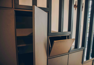 Foto van een open kast en lade in een eigentijds lodge-interieur met verticale houten lamellen op de achtergrond.