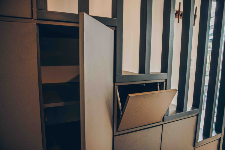 Foto de un gabinete abierto y un cajón en un interior moderno de lodge con listones de madera verticales al fondo.