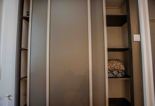 Een kast in een lodgekamer met open legplanken en daarop keurig opgevouwen dekens of donsdekens.