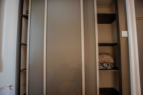 Ein Kleiderschrank in einer Lodge mit offenen Regalen, die gefaltete Decken oder Bettwäsche zeigen.