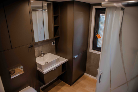 Modernes Badezimmer in einer Lodge mit braunen Schränken, eckigem Waschbecken, Spiegel und Fenster.