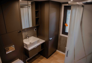 Modernes Badezimmer in einer Lodge mit braunen Schränken, eckigem Waschbecken, Spiegel und Fenster.