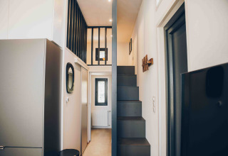 Innenaufnahme einer modernen Lodge mit schmaler Treppe, Galerie und minimalistischem Design in hellen Tönen.