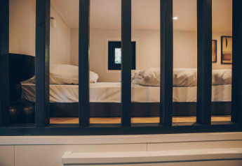 Blick durch schwarze Gitter in ein gemütliches Lodge-Zimmer mit einem großen Bett und Kissen.