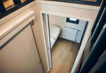 Vista dall'alto su una piccola camera da letto con pavimento in legno, radiatore e letto in un lodge.