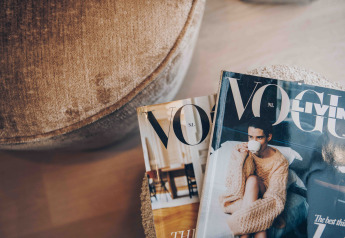 Zwei Magazine, darunter die Vogue, liegen auf einem weichen Tisch neben einem Stuhl in einer Lodge.